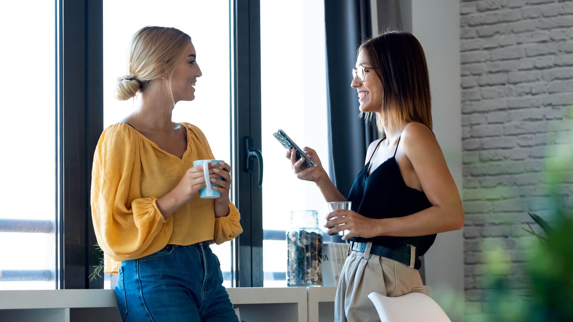 Dos mujeres conversando con naturalidad en una oficina, ilustrando cómo la comunicación cotidiana también fortalece la marca personal, tema abordado por Gabriel Patrizzi en su blog
